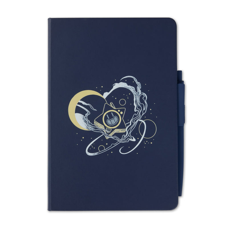 A navy blue notebook with a matching pen in its side pocket, featuring a central graphic of a gold crescent moon, Glowby, and white swirling cosmic lines.