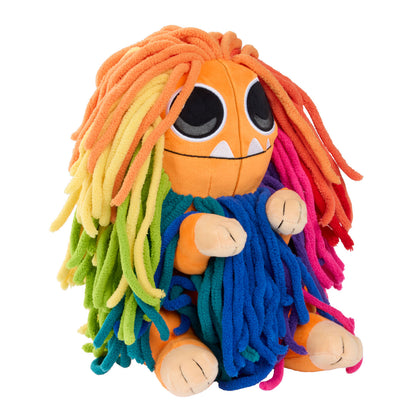 A colorful plush toy with an orange round head, large black eyes, small white teeth, and long fuzzy yarn-like hair and clothing in rainbow colors including yellow, green, blue, pink, and red.